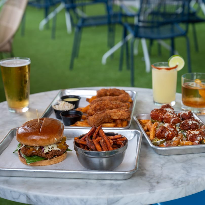 Highline Park's bar-and-grill spread: chicken sandwich, sweet potato fries, tenders, loaded fries, and drinks.